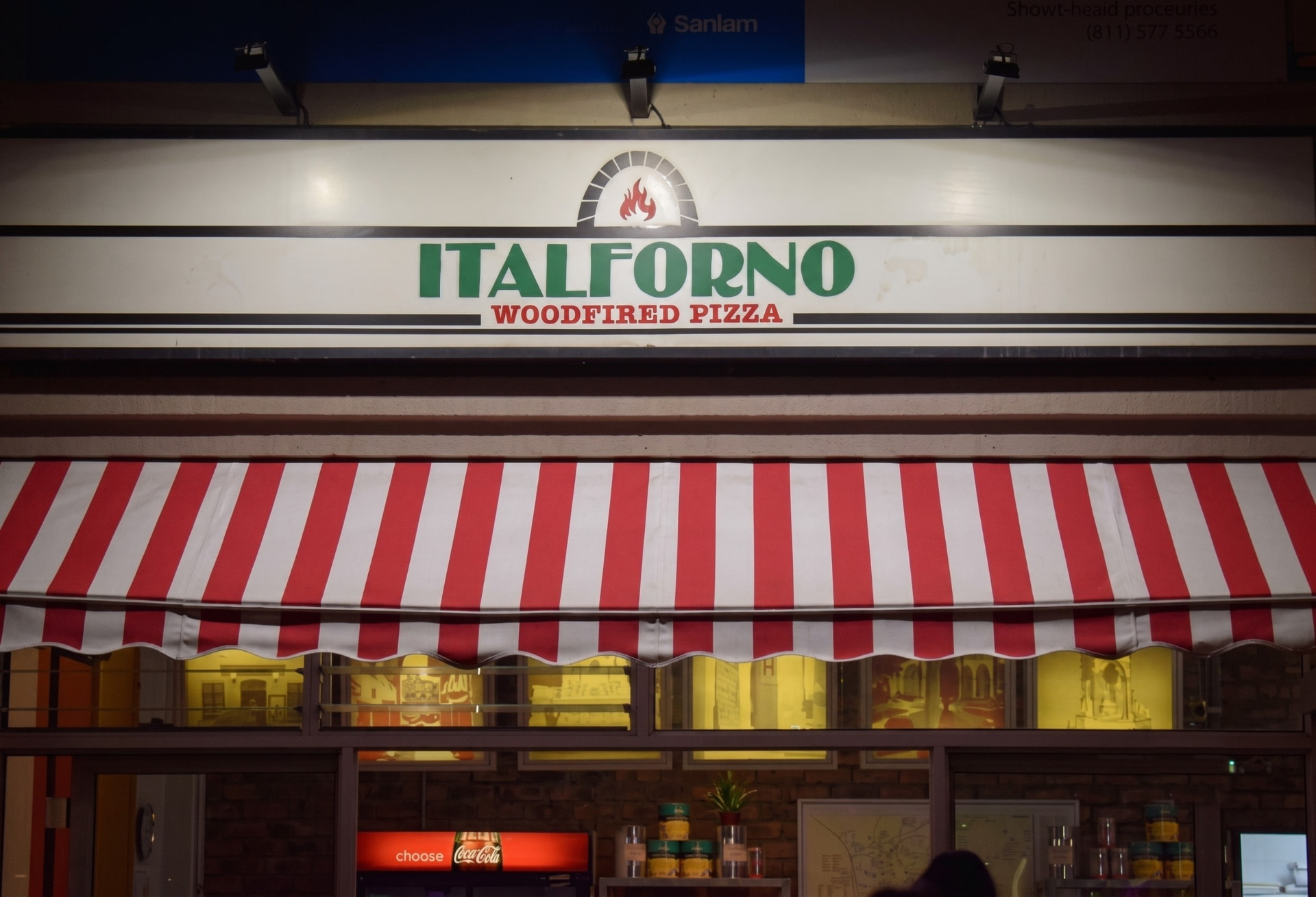 Italforno Woodfired Pizza sign above the red-and-white striped awning
