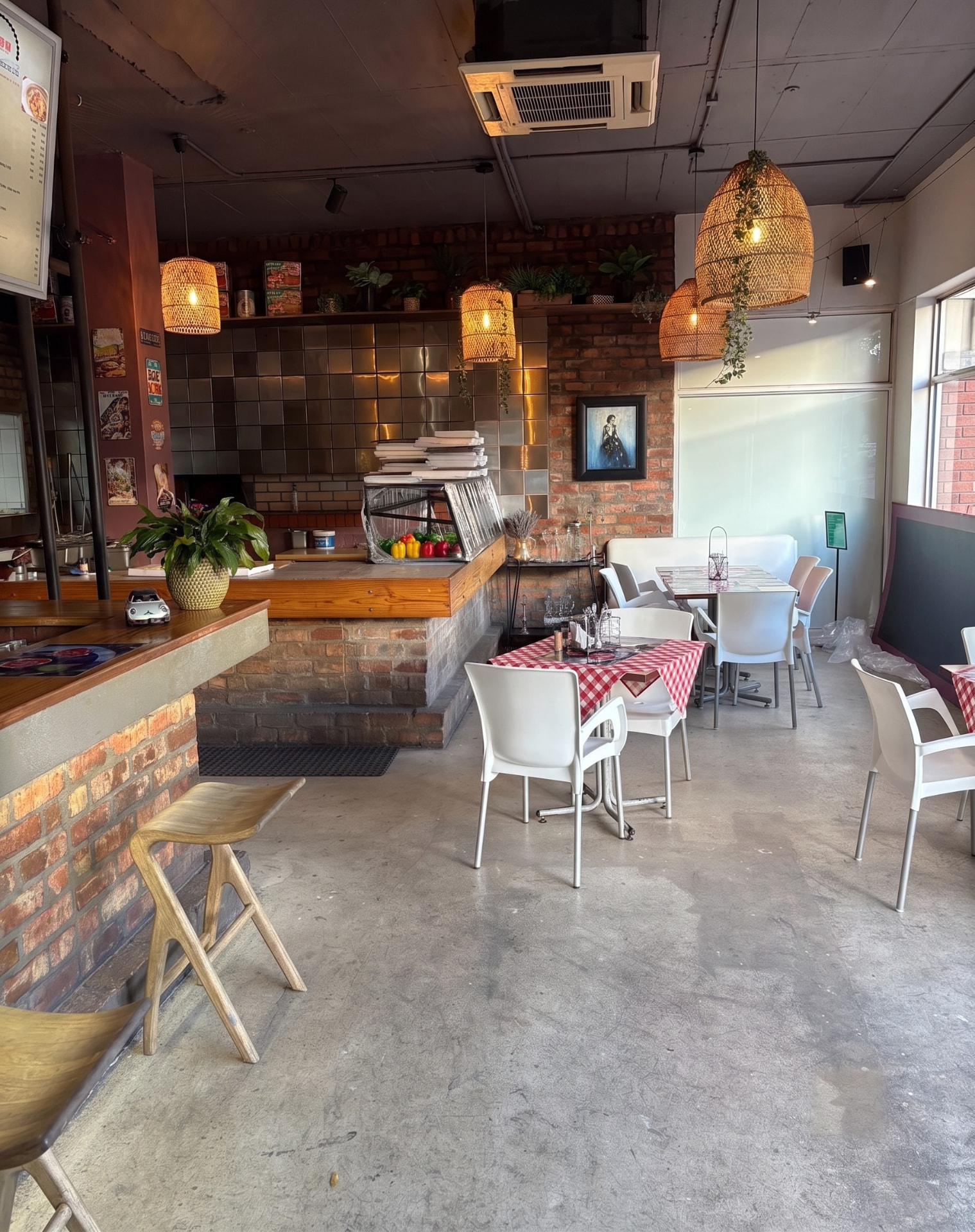 Inside Italforno — exposed brick, checked tablecloths and the pizza counter